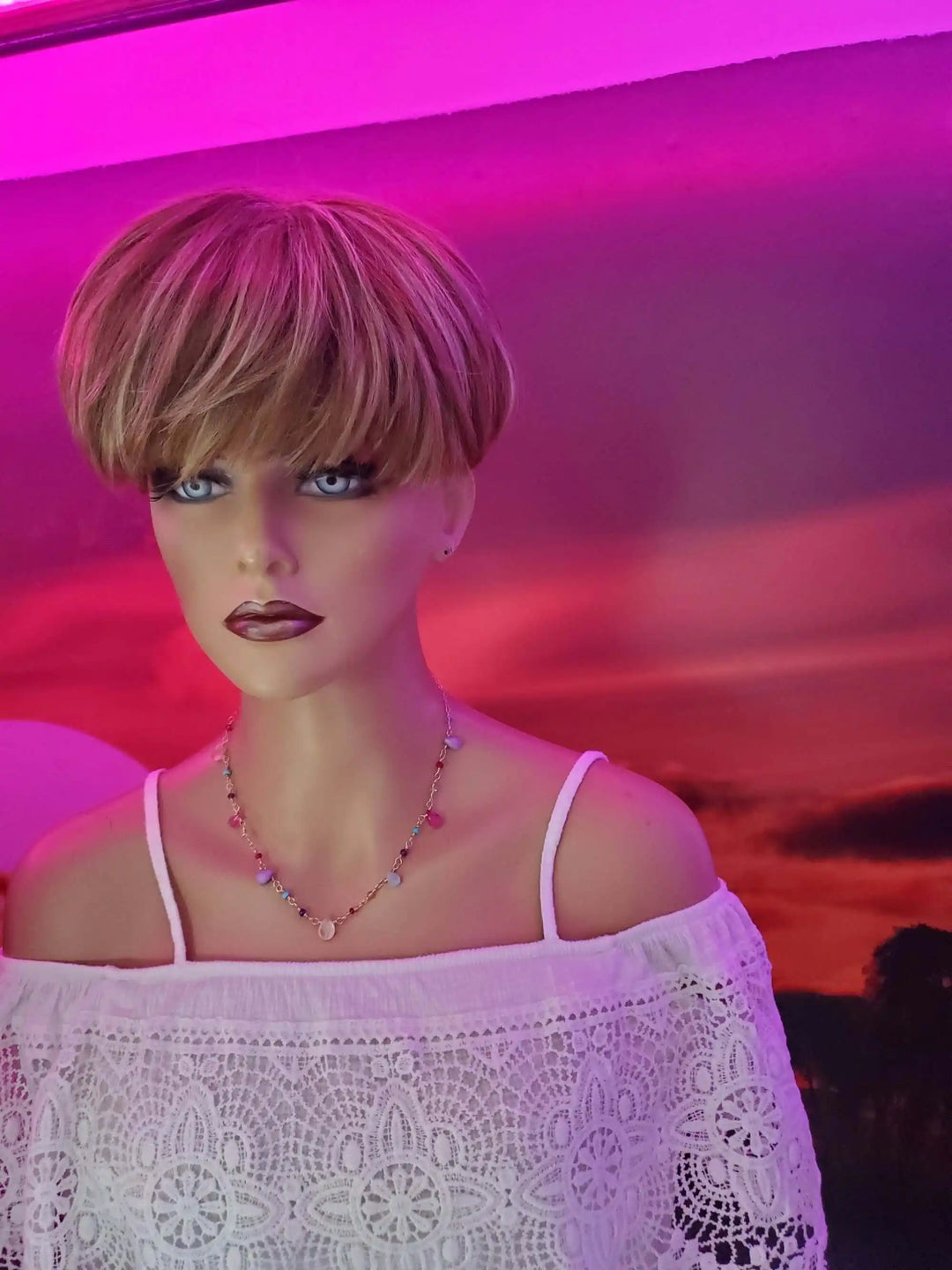 Mannequin with stylish bob haircut wearing an Adjustable Golden Wire Wrapped Kunterbunt Gemstone Necklace against a colorful background.