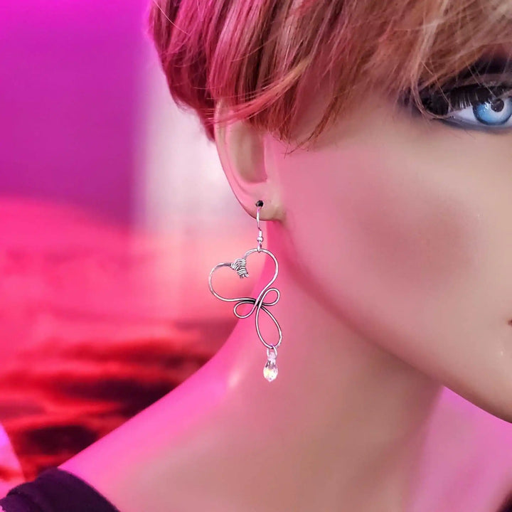 Handmade Copper Wire Sculpted Heart Crystal Drop Earrings displayed on a mannequin with a pink background.