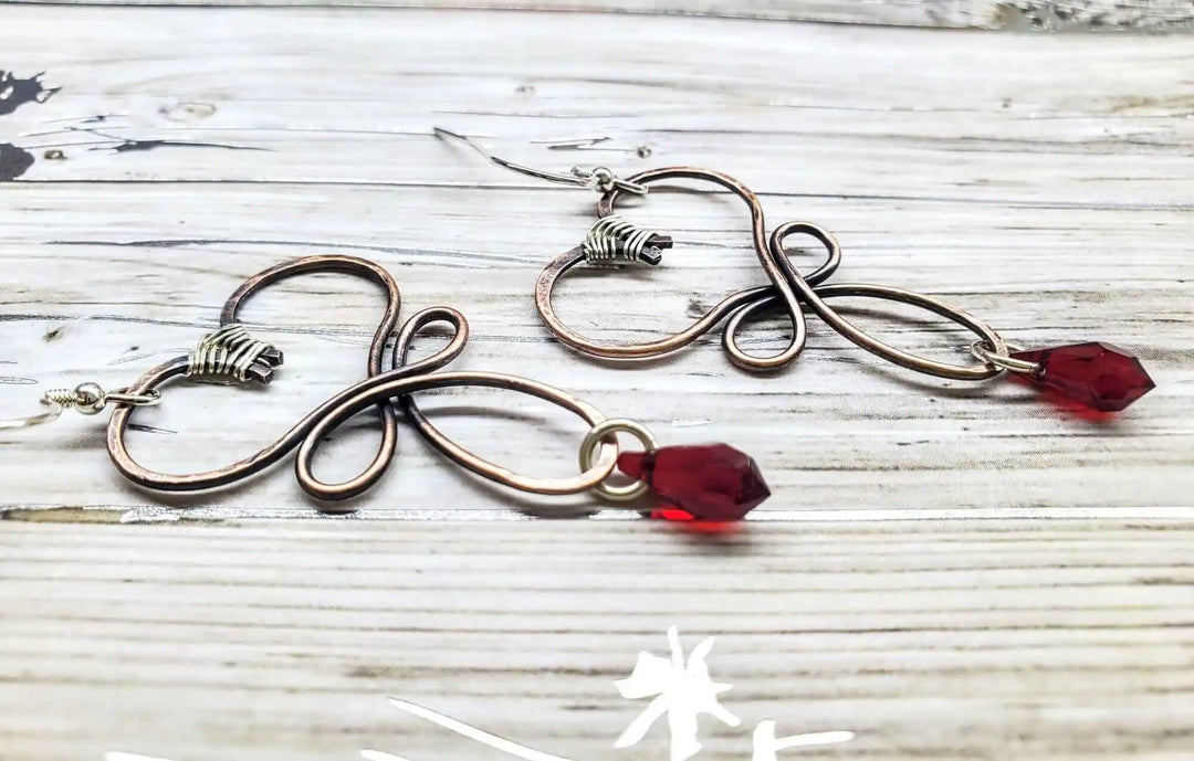 Handmade Copper Wire Sculpted Heart Crystal Drop Earrings featuring red crystal drops and sculptural metalwork details.
