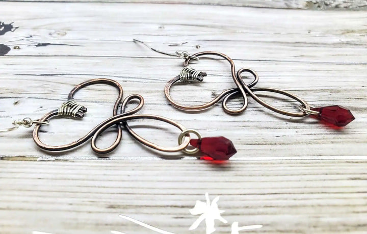 Handmade Copper Wire Sculpted Heart Crystal Drop Earrings featuring red crystal drops and sculptural metalwork details.