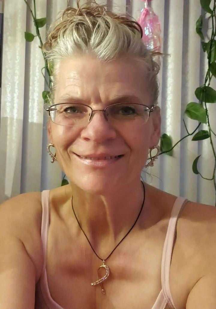 A woman wearing Handmade Copper Silver Pink Crystal Ribbon Jewelry Set with earrings and necklace, smiling in a softly lit room.