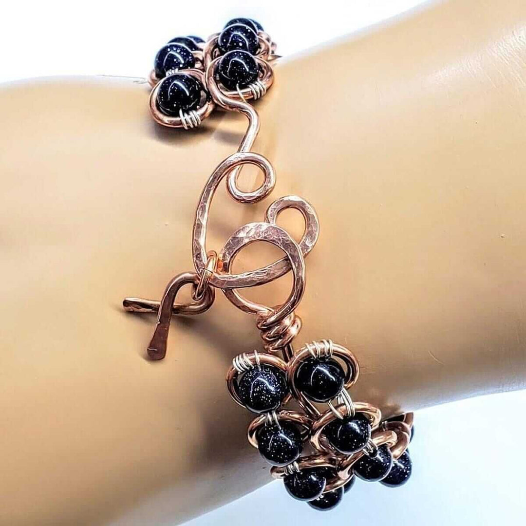 Wire Sculpted Blue Beaded Infinity Child Abuse Bangle featuring black sandstone beads and copper detailing.