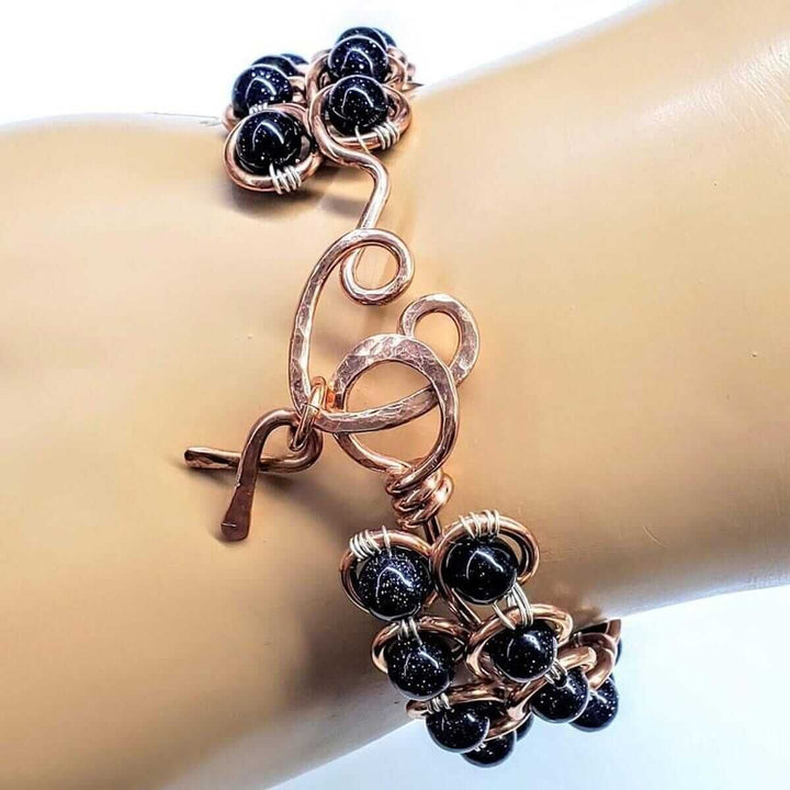Wire Sculpted Blue Beaded Infinity Child Abuse Bangle featuring black sandstone beads and copper detailing.
