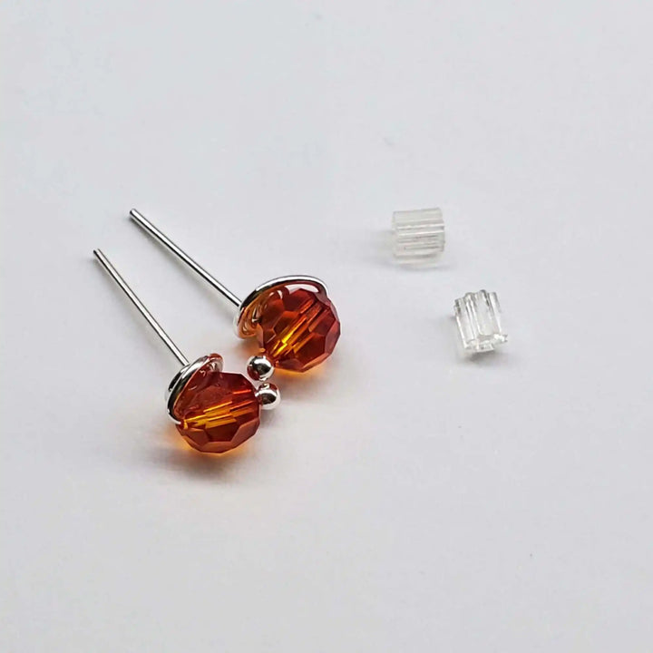 Handmade 6mm Silver Spiral Crystal Stud Earrings with orange crystals on a white background.