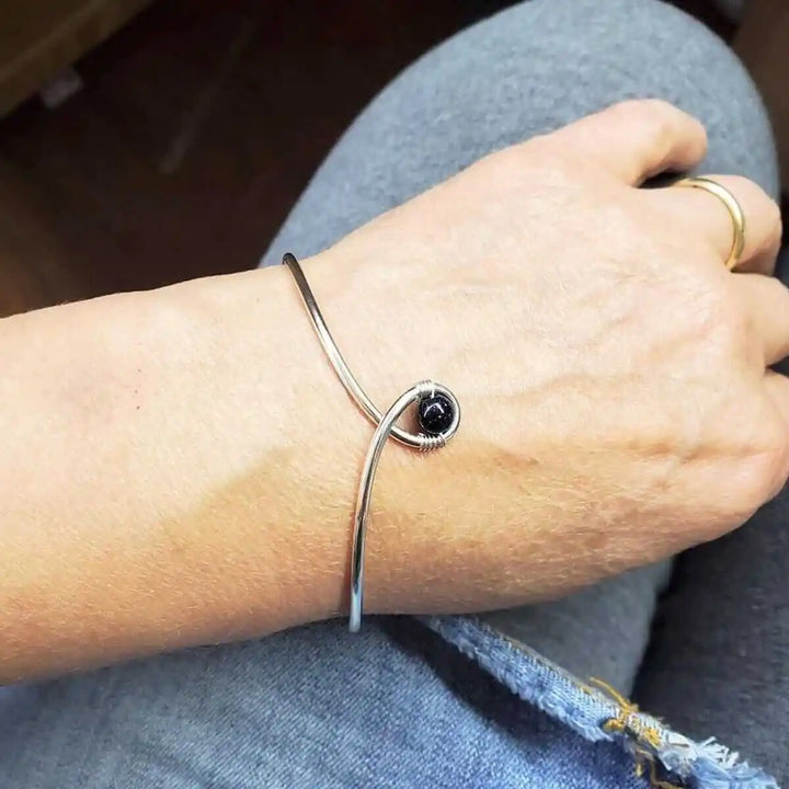Silver Blue Bead Child Abuse Awareness Ribbon Bangle worn on wrist, showcasing elegant design and sparkling bead.