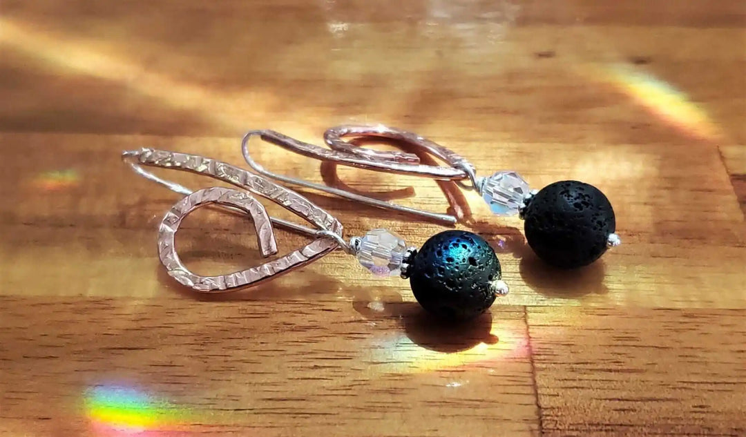 Embossed Copper Butterfly Wing Lava Rock Bead Earrings featuring black lava beads and sparkling crystals on a wooden surface.