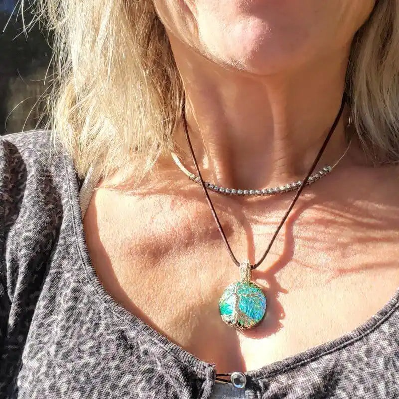 Handmade tree of life dichroic pendant necklace worn by a woman, showcasing its vibrant colors and unique design.