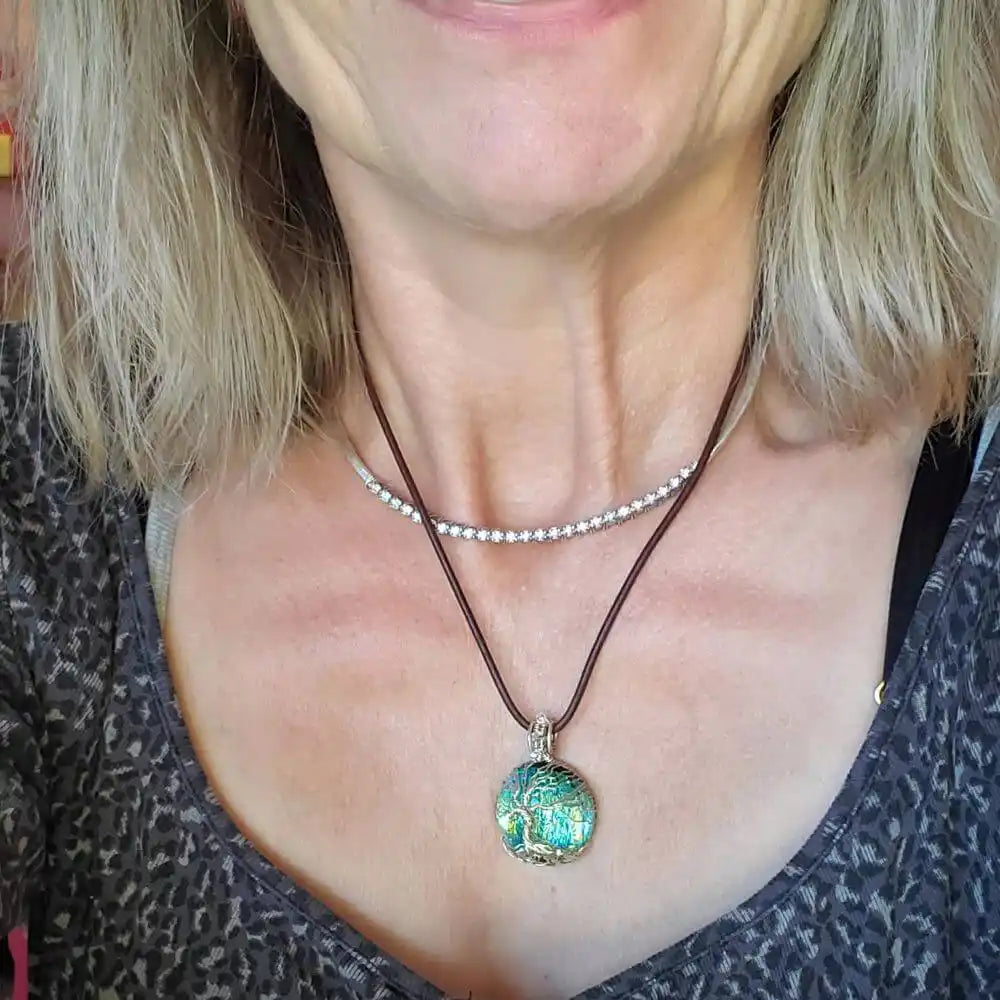 Handmade tree of life dichroic pendant necklace worn on a person, showcasing its vibrant colors and unique design.