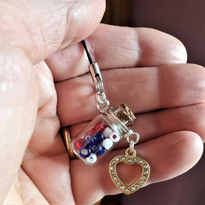 Handmade Silver Wire Wrapped Red White Blue Bottle Charm featuring patriotic beads and heart pendant in hand.