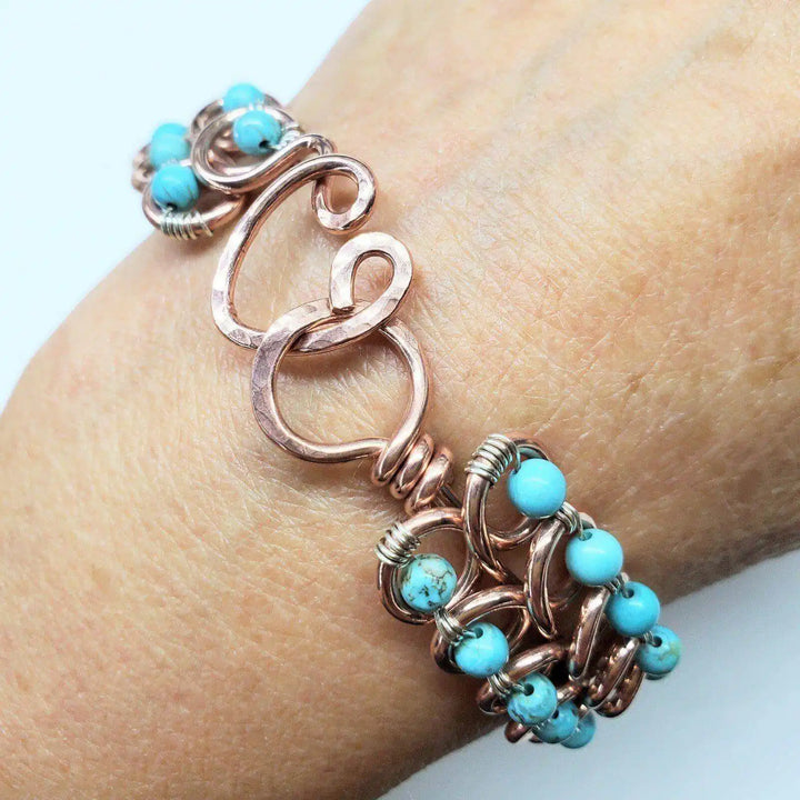 Wire Wrapped Turquoise Copper Infinity Heart Closure Bangle elegantly displayed on a wrist, showcasing turquoise beads and heart design.