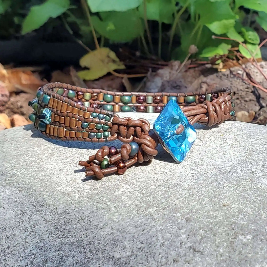 Intricate Bead Woven Swarovski Crystal Button Glam Bracelet featuring a large aqua crystal on a leather wrap.