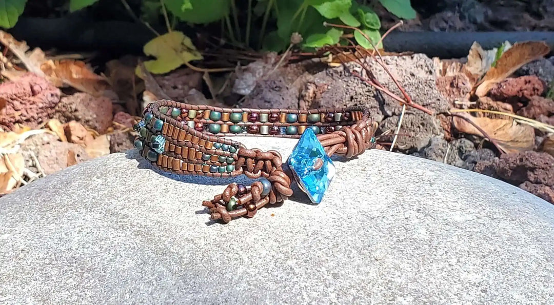 Intricate Bead Woven Swarovski Crystal Button Glam Bracelet shown on a stone surface with colorful beads and a blue crystal.