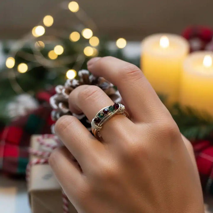 Limited edition 2026 silver wire wrapped Christmas ring worn on a hand, with festive decorations in the background.