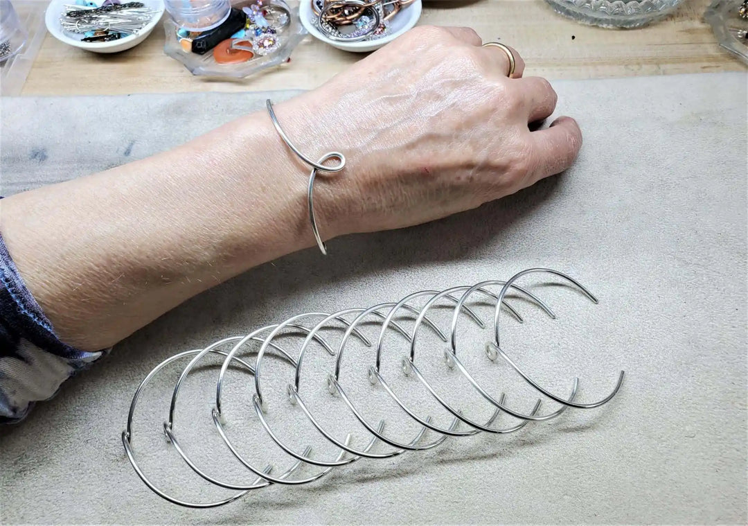Handmade Wire Sculpted Silver Teardrop Bangle worn on wrist with multiple silver bangles displayed.