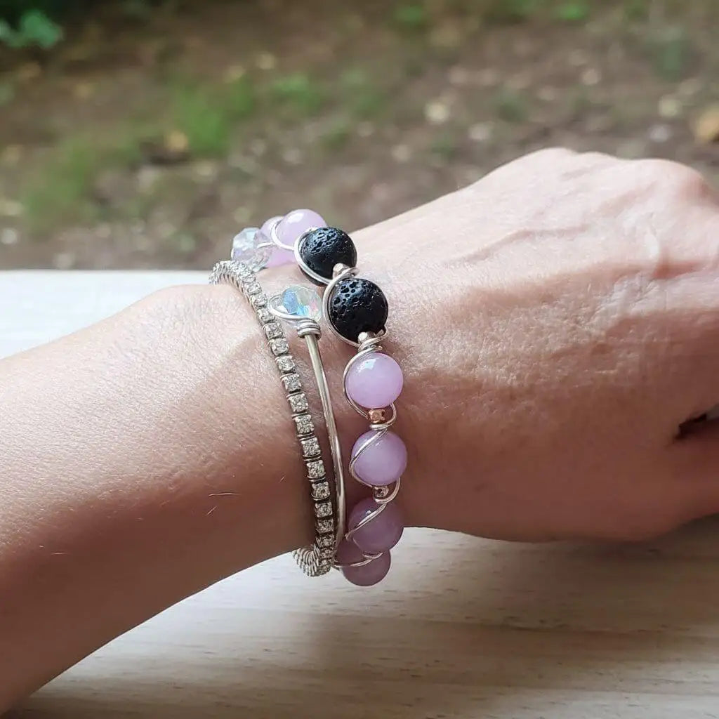 Silver Spiral Twist Wrap Purple Lava Rock Bangle Bracelet worn on wrist alongside other bracelets.