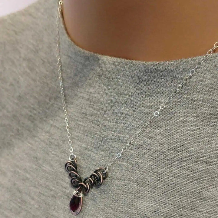 Silver and Copper Wire Sculpted Purple Crystal Drop Necklace displayed on a mannequin wearing a grey shirt.