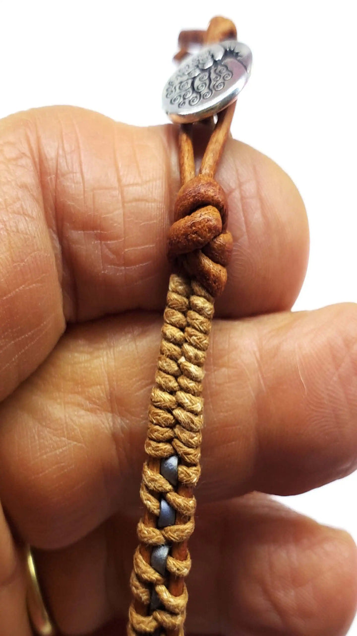 Handmade Tree of Life leather wrap bracelet featuring intricate brown and gray seed beads attached to a hand.