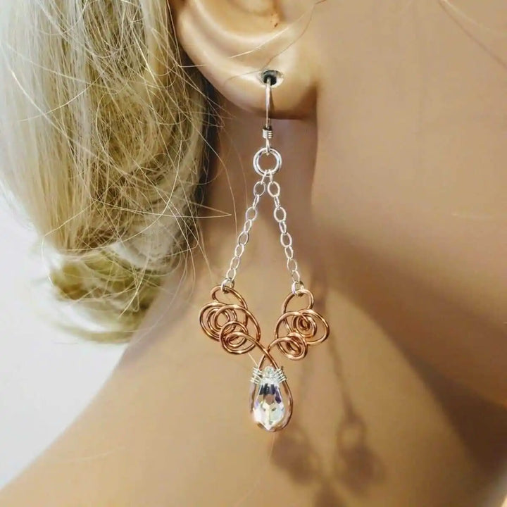 Wire Sculpted Crystal Drop Chandelier Angel Wing Earrings hanging elegantly on a mannequin ear, showcasing their unique design.