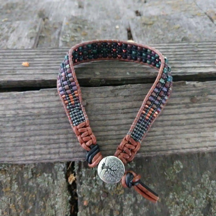 X-Large Leather Intricate Beaded Tree Of Life Bracelet showcased on a rustic wooden surface, featuring unique beadwork and leather.