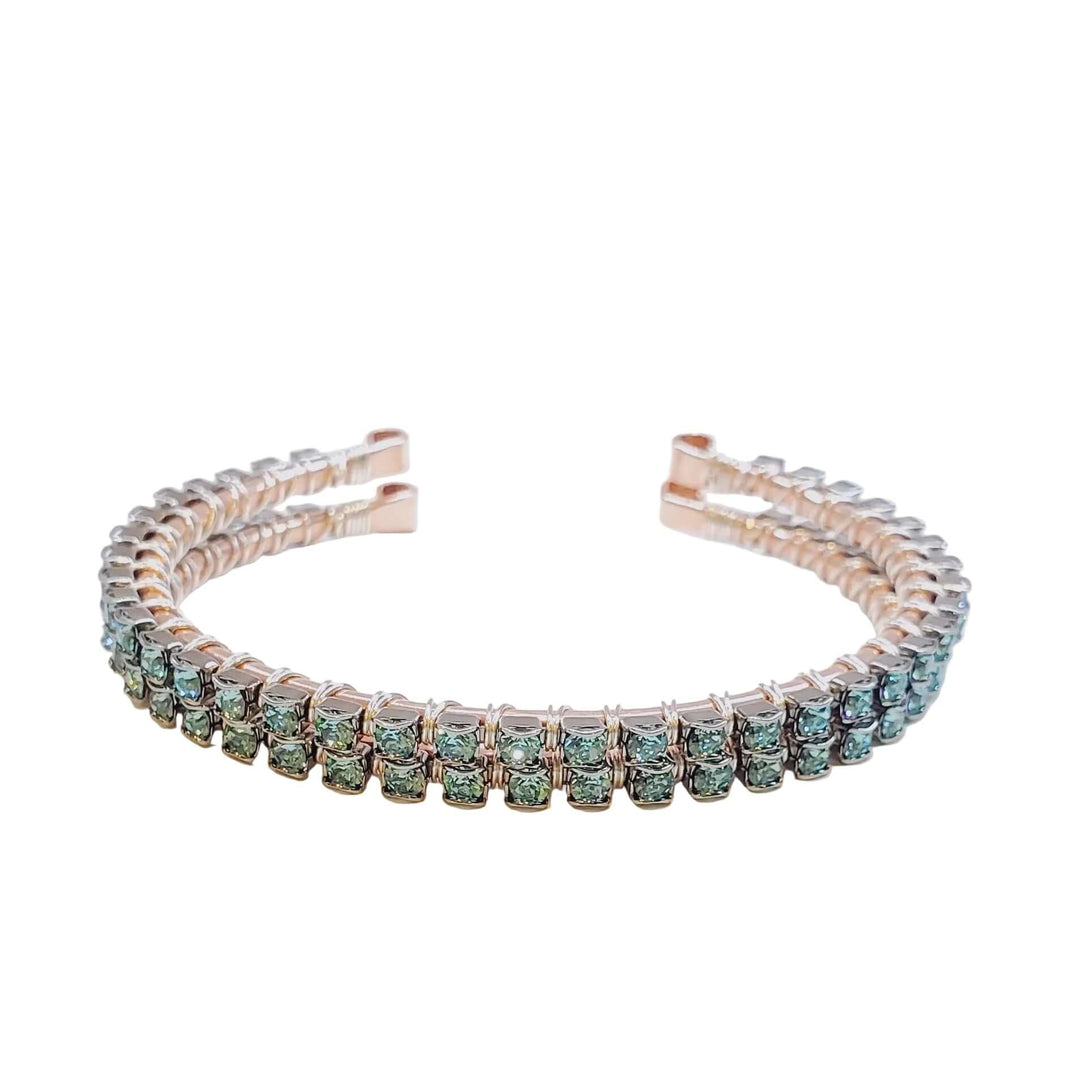 Silver bracelet with green gemstones on a light gray background