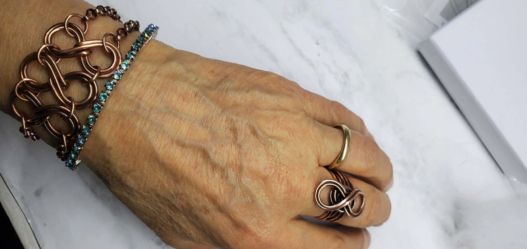 Wire Wrapped Turquoise Crystal Tennis Bangle Bracelet worn on a hand alongside other copper bracelets.
