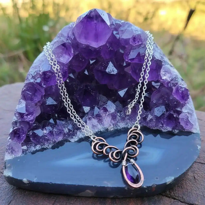 Silver and Copper Wire Sculpted Purple Crystal Drop Necklace showcased on amethyst crystals.