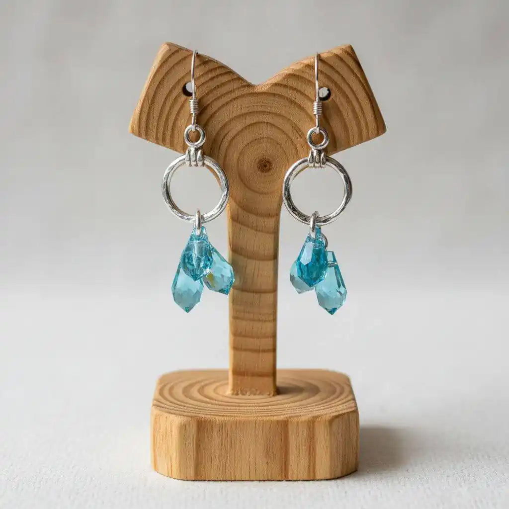 925 Silver Hammered Aqua Crystal Cascading Drop Earrings displayed on a wooden stand, showcasing aqua Swarovski crystals.