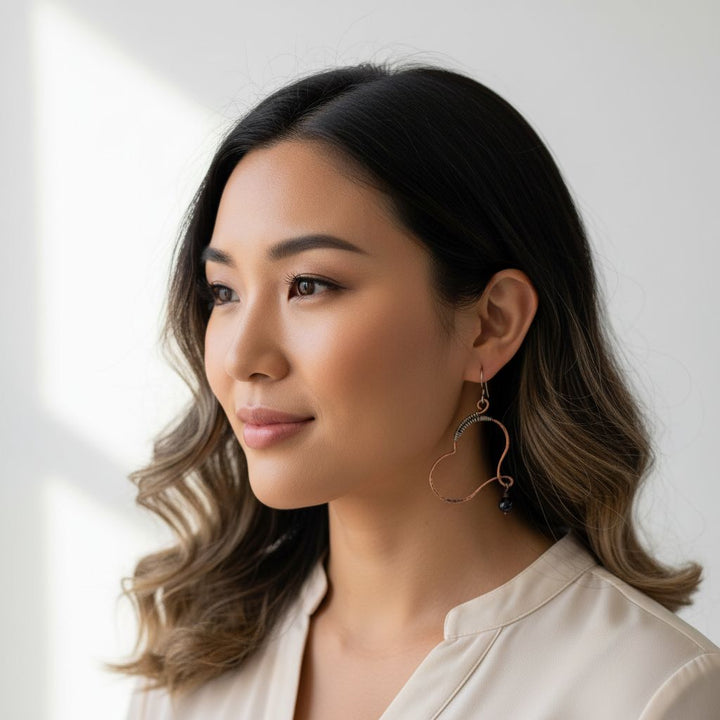 A model showcases Sculpted Copper Butterfly Wing Abuse Survivor Earrings featuring sterling silver and black Swarovski crystals.