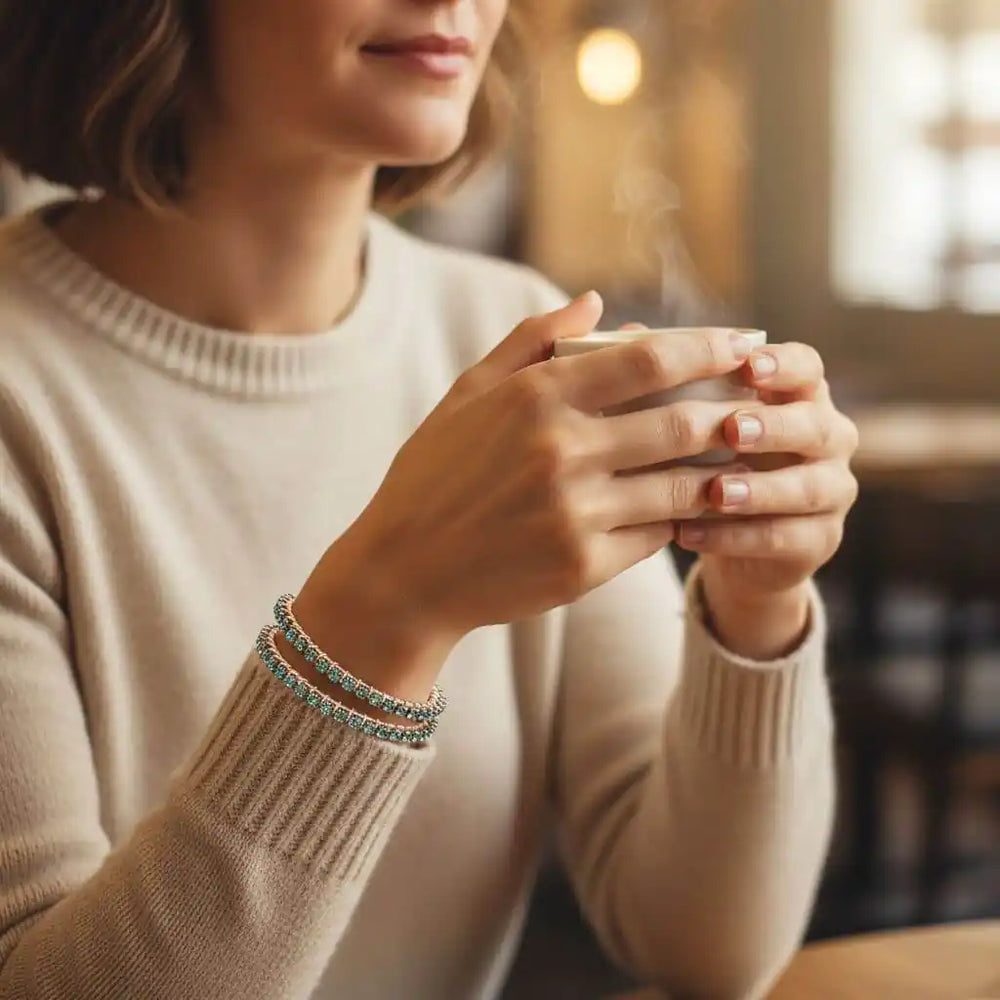 Woman holding a cup while wearing a Wire Wrapped Turquoise Crystal Tennis Bangle Bracelet and other bracelets.