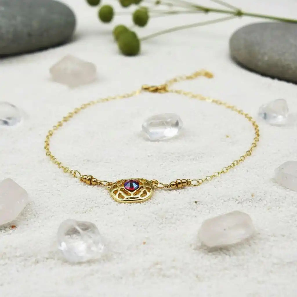 Red Crystal 14 K Gold Filled Adjustable Filigree Choker showcased with crystals and pebbles on a sandy background.