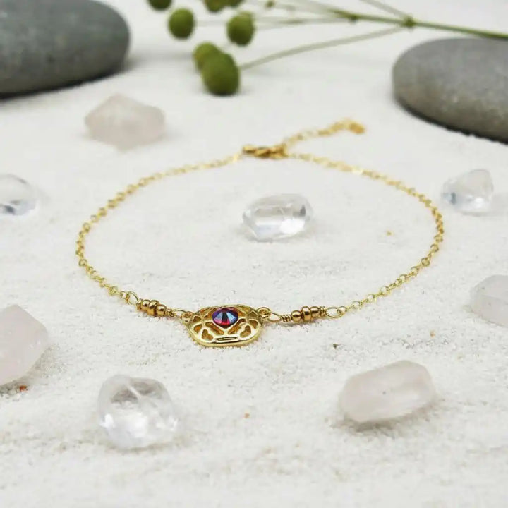 Red Crystal 14 K Gold Filled Adjustable Filigree Choker showcased with crystals and pebbles on a sandy background.