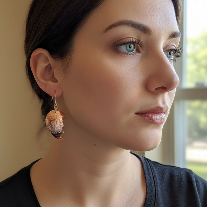 Handmade Sculpted Copper Broken Heart Earrings worn by a woman, showcasing artisan metalwork and emotional expression.