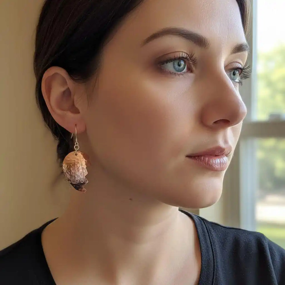 Handmade Sculpted Copper Broken Heart Earrings worn by a woman, showcasing artisan metalwork and emotional expression.