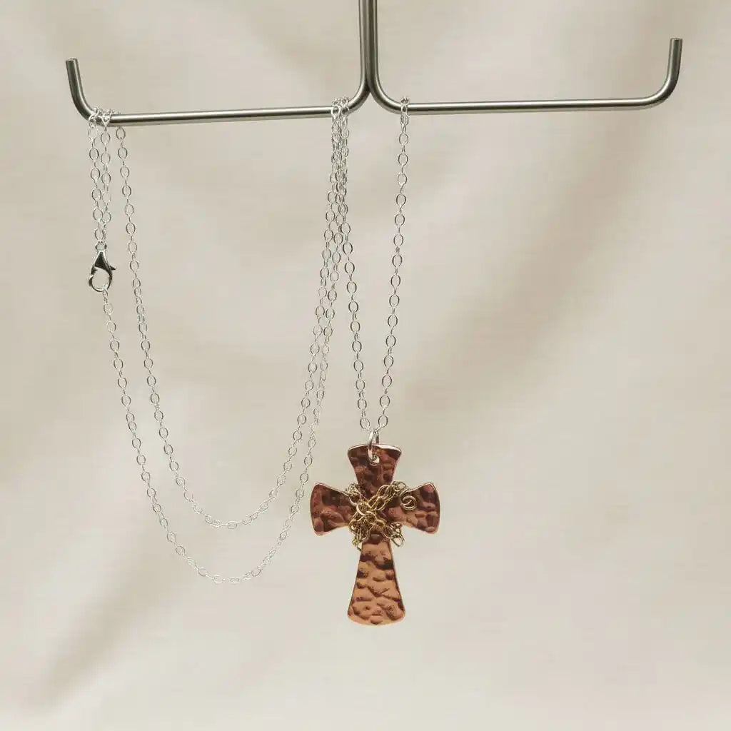 Chained Hammered Copper Cross Necklace For Him Or Her elegantly displayed on a hook, showcasing its unique design.