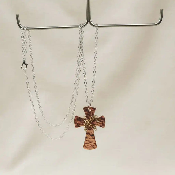 Chained Hammered Copper Cross Necklace For Him Or Her elegantly displayed on a hook, showcasing its unique design.