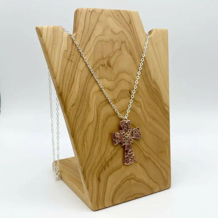 Chained Hammered Copper Cross Necklace For Him Or Her displayed on a wooden stand, showcasing its unique handcrafted design.