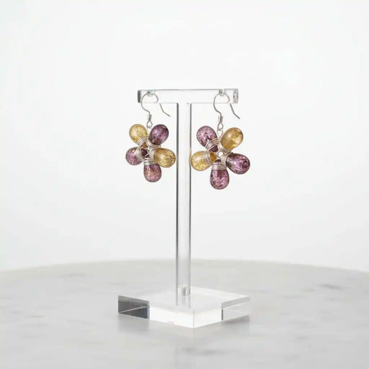 Purple and Yellow Flower Sterling Silver Earrings displayed on a stand, showcasing their floral design and colorful glass beads.