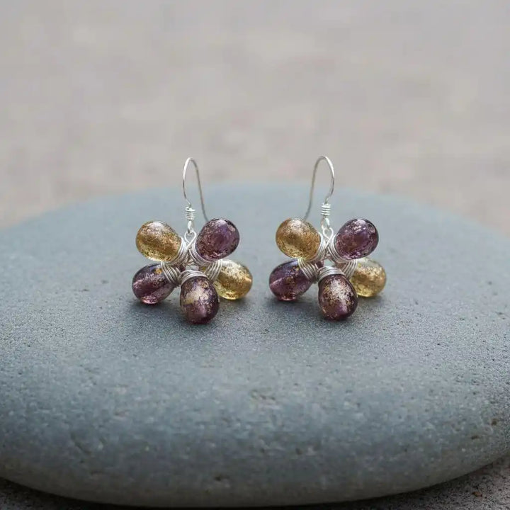 Purple and Yellow Flower Sterling Silver Earrings showcased on a smooth stone surface.