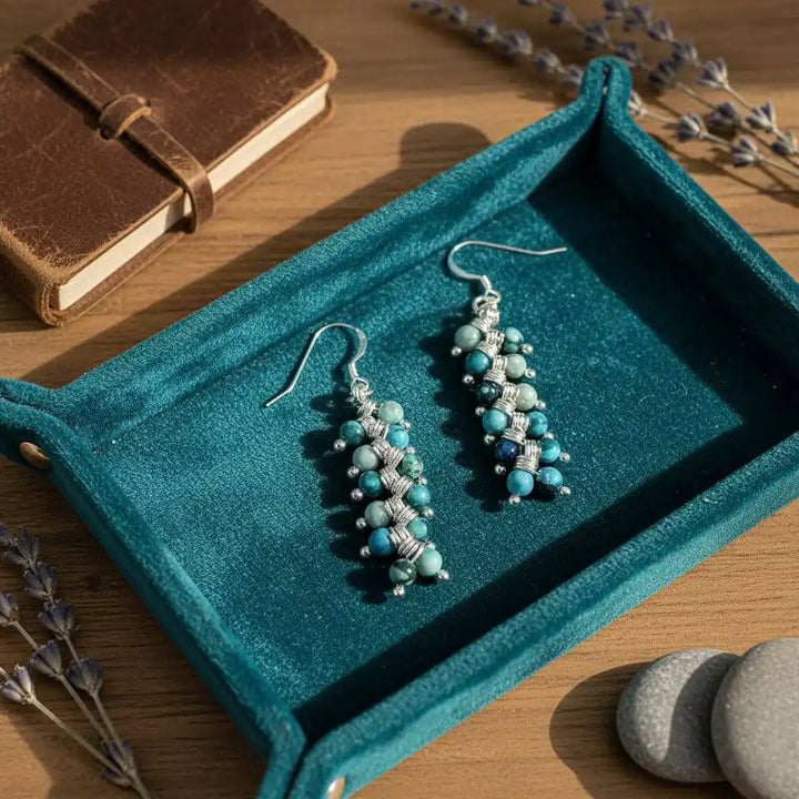 Seen On Jane The Virgin Silver Turquoise Wire Coil Earrings displayed on a teal fabric tray with a notebook.