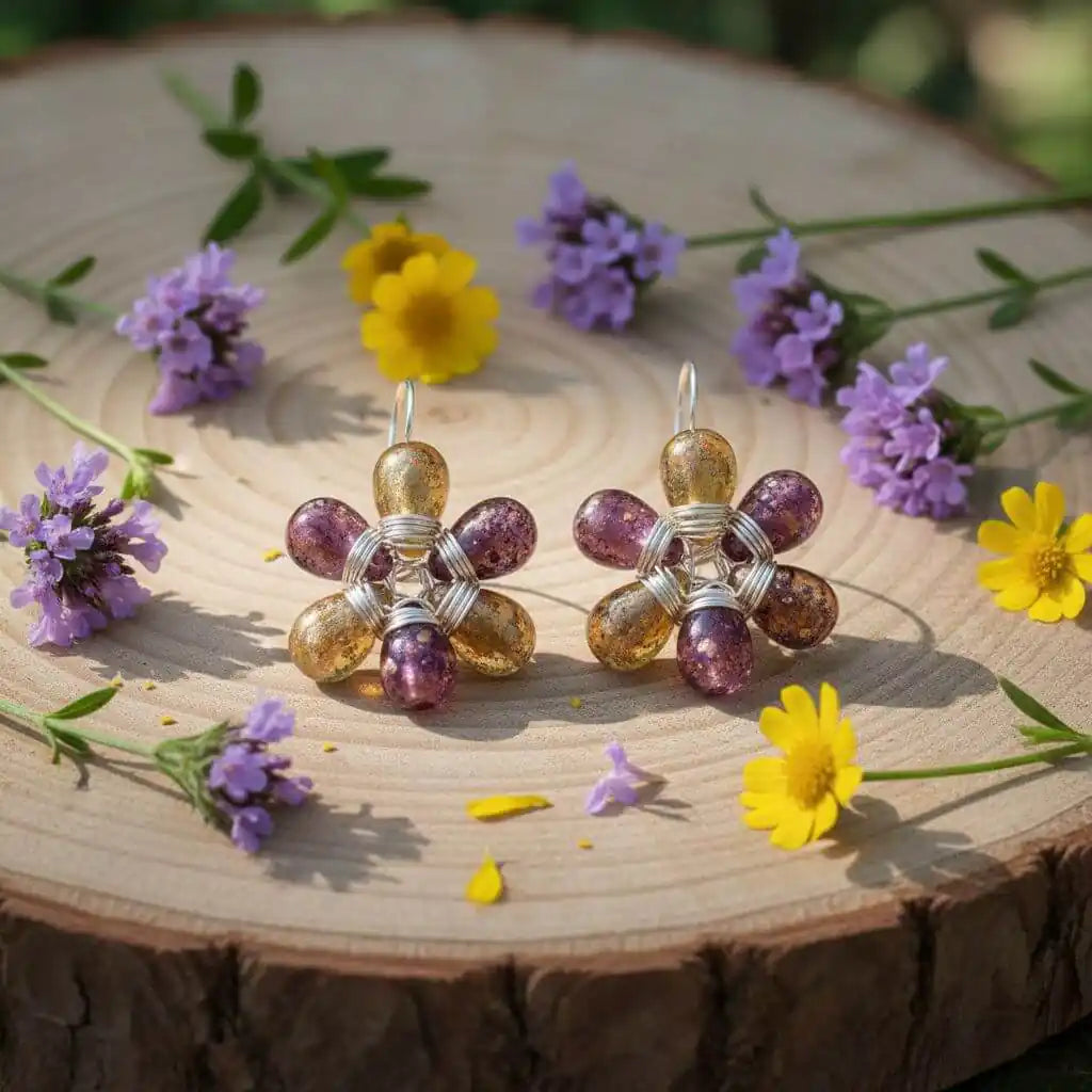Purple and Yellow Flower Sterling Silver Earrings displayed on a wooden surface surrounded by wildflowers.