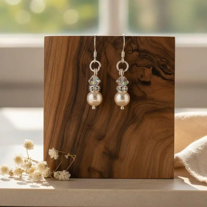 Various Color Swarovski Crystal Pearl Stack Earrings displayed on a wooden block with a blurred background.