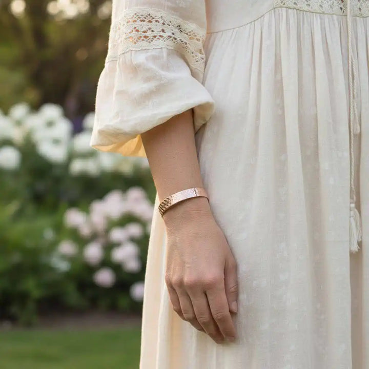 His and Her Copper Embossed Weave Cuffs 16 Gauge worn by a woman in a garden, showcasing artisan-crafted jewelry.