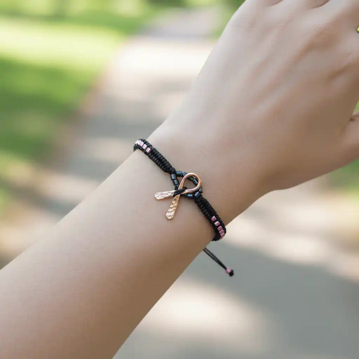 Copper Ribbon Black Pink Braided Breast Cancer Bracelet worn on a wrist in a natural setting.
