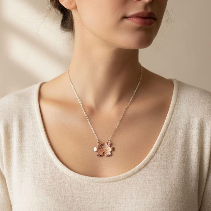 Woman wearing a delicate necklace with a small pendant against a neutral background