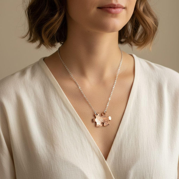 Necklace with a pendant worn by a person in a white top against a neutral background