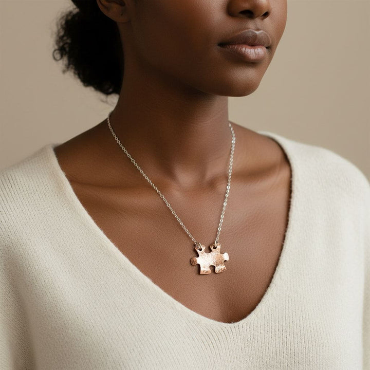 Woman wearing a necklace with a puzzle piece pendant on a beige background