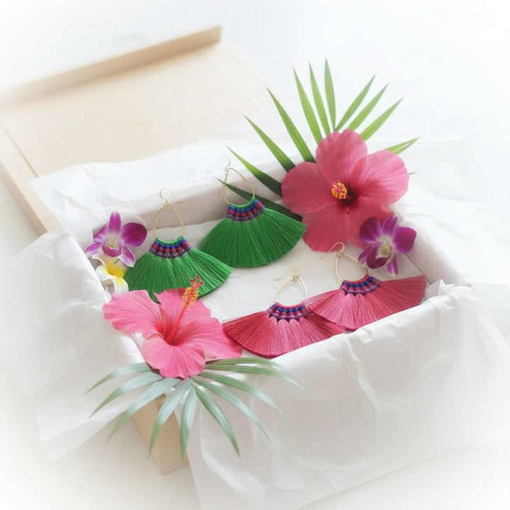 Handmade Hawaii Hula Skirt Rayon Silk Tassel Hoop Earrings displayed in packaging with tropical flowers.