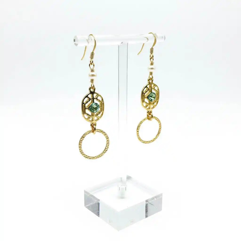 14 KT Gold Filled Green Crystal Circle Filigree Earrings displayed on a clear stand showcasing their elegant design and craftsmanship.