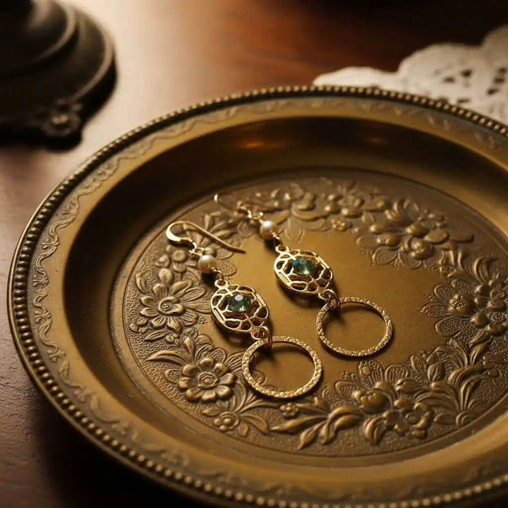 14 KT Gold Filled Green Crystal Circle Filigree Earrings displayed on an ornate plate with floral design.