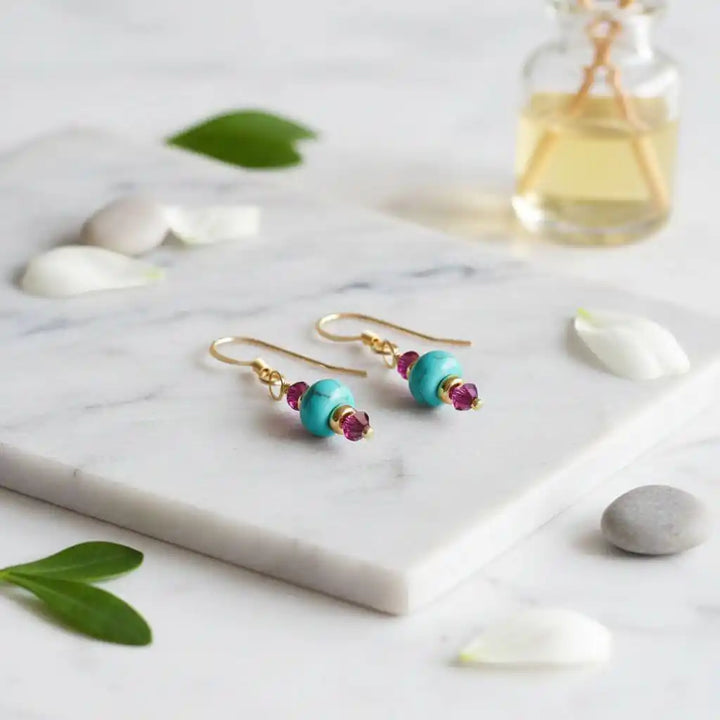 Hot Pink and Turquoise Gemstone14 K Gold Filled Earrings displayed on a marble surface with natural elements.